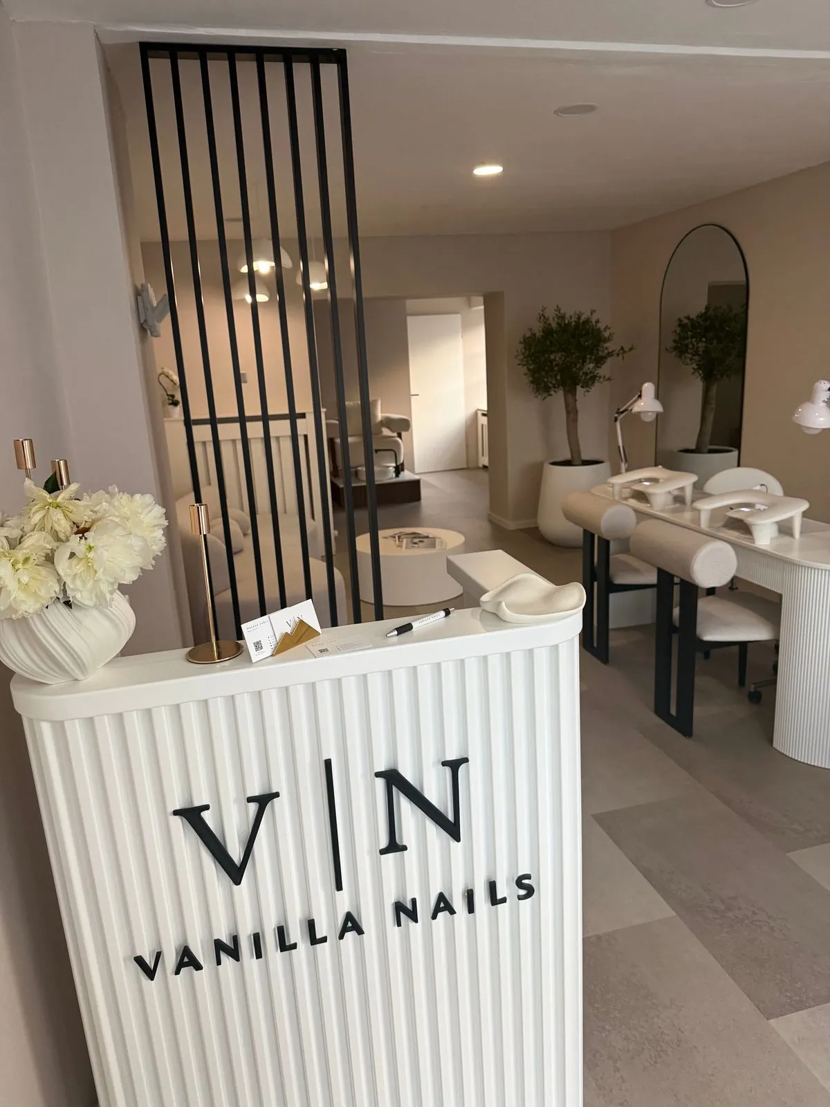 Empfangstresen eines Nagelstudios mit Maniküre-Plätzen im Hintergrund
